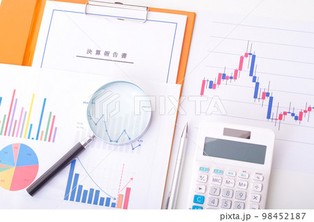 電卓と決算報告書と株価チャートと虫メガネ 98452187