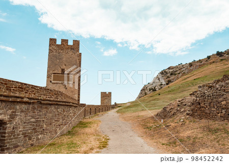 A large wall with a tower against a light blue sky. A large wall with a tower against a light blue sky. 98452242