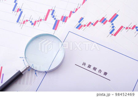 決算報告書と株価チャートと虫メガネ 98452469