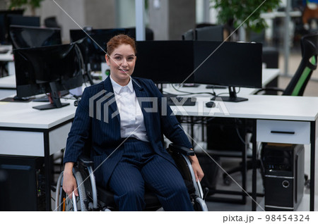 Caucasian woman wheelchair in open space office. 98454324