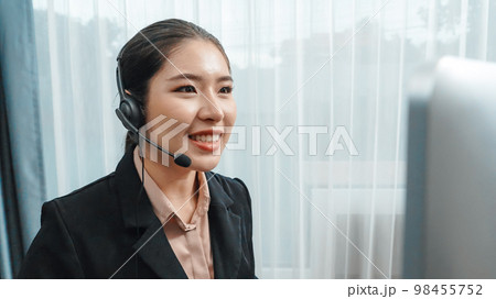 Young enthusiastic female customer support operator put on headphone. 98455752