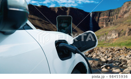 Progressive concept of energy sustainability by EV car in the waterfall. Progressive concept of energy sustainability by EV car in the waterfall. 98455936