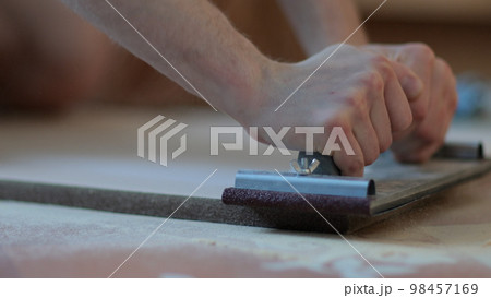 Carpenter grinders sanding wooden board. Close up of hands Carpenter grinders sanding wooden board. Close up of hands 98457169