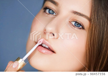 Beauty, makeup and skincare cosmetics model face portrait, beautiful woman applying lip gloss, cosmetic product and glamour make-up closeup 98457356