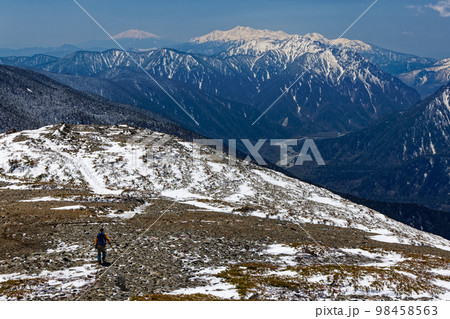 残雪の北アルプス・蝶ヶ岳稜線を行く登山者と乗鞍岳・御嶽の眺め 98458563