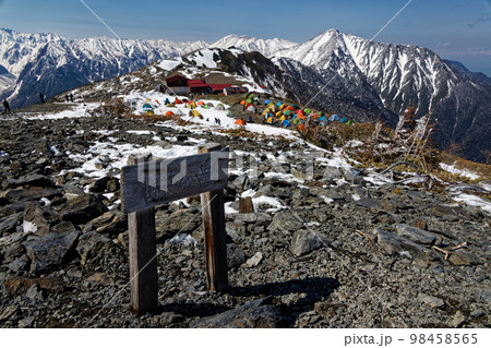 残雪の北アルプス・蝶ヶ岳山頂から見る蝶ヶ岳ヒュッテのテント場と常念岳 98458565