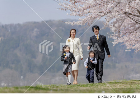 桜の咲く遊歩道を歩く入学入園の親子 98459692