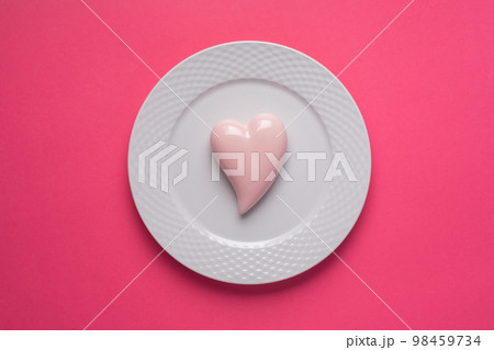 Pink heart on a plate on pink background. Simple concept for Valentine's day holiday Pink heart on a plate on pink background. Simple concept for Valentine's day holiday 98459734