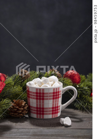 Red mug with hot chocolate on top of which pieces of marshmallows float on wooden background 98459753
