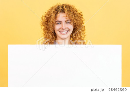 Smiley woman with curly hair holding a blank panel Smiley woman with curly hair holding a blank panel 98462360