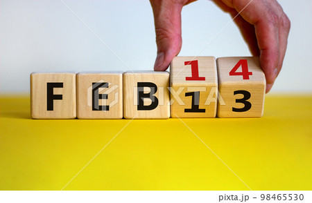 February 14 valentines day symbol. Hand turns cubes and changes the word 'Feb 13' to 'Feb 14'. Beautiful yellow table, white background, copy space. February 14 Valentines day concept. 98465530