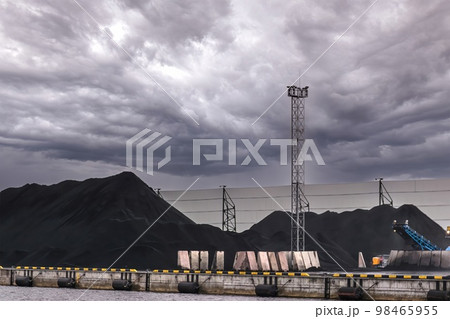 A huge amount of coal in the sea trading port. Coal is delivered here in industrial wagons, distributed throughout the port, unloaded. 98465955