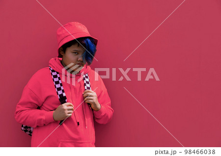 Back to school. A teenage girl with blue hair in pink hoodie, a Panama hat with a backpack. A high school kid. 98466038