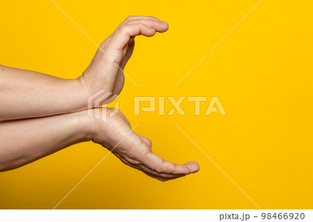 Strong male hands making the gesture of a kame hame, ready to launch a vital wave of energy. Isolated on yellow background. Strong male hands making the gesture of a kame hame, ready to launch a vital wave of energy. Isolated on yellow background. 98466920