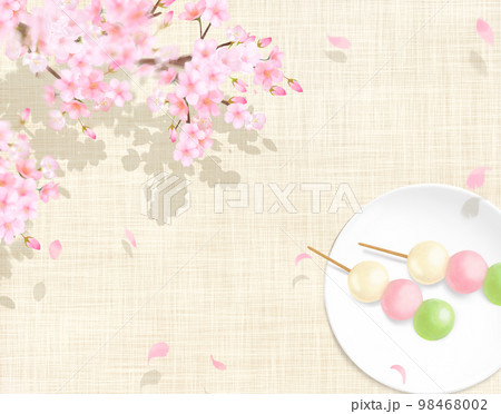 桜とウッドデッキの上に麻布のテーブルクロスとお皿の上に3色団子のフレーム壁紙背景素材 98468002