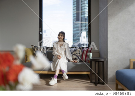 オフィスのソファでくつろぐ女性。コーヒーカップあり。 98469385