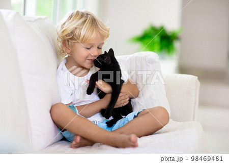 Child playing with baby cat. Kid and kitten. 98469481