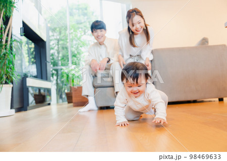 ハイハイをする赤ちゃんと子供の成長を見守る両親 98469633