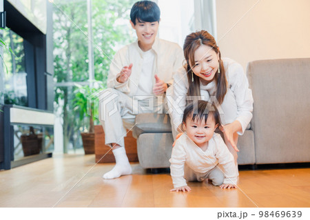 ハイハイをする赤ちゃんと子供の成長を見守る両親 ハイハイをする赤ちゃんと子供の成長を見守る両親 98469639
