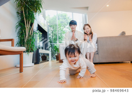 ハイハイをする赤ちゃんと子供の成長を見守る両親 ハイハイをする赤ちゃんと子供の成長を見守る両親 98469643