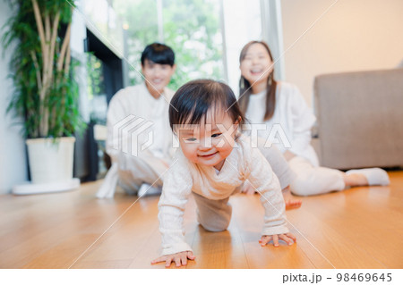 ハイハイをする赤ちゃんと子供の成長を見守る両親 ハイハイをする赤ちゃんと子供の成長を見守る両親 98469645