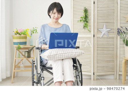 家でパソコンを使う車椅子に乗った障がい者女性 家でパソコンを使う車椅子に乗った障がい者女性 98470274