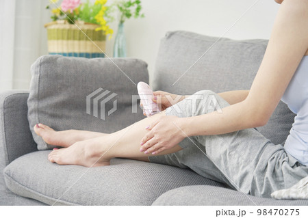家で足のセルフ脱毛をする女性　顔無し 98470275