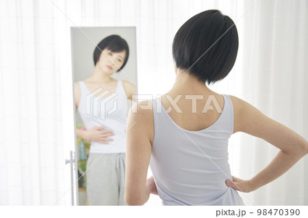 鏡を見て体型をチェックする女性 98470390