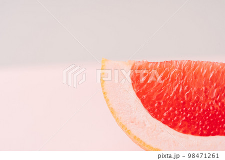 Grapefruit slice against green-pink background Grapefruit slice against green-pink background 98471261