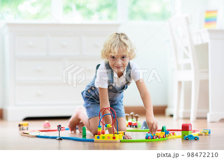 Kids play wooden railway. Child with toy train. 98472210