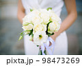 Beautiful fresh wedding bouquet of roses and other flowers in beige light colors in the hands of the bride. Soft focus, background blur. 98473269