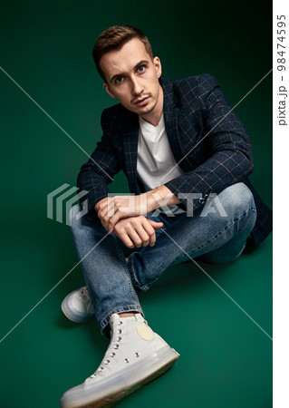 handsome man in plaid jacket sitting on the floor handsome man in plaid jacket sitting on the floor 98474595