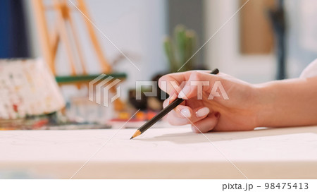 Drawing class. Art hobby. Creative occupation. Closeup of female artist hand sketching artwork with pencil on white canvas at workplace with free space. 98475413