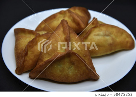Meat pies on a white plate. Belyashi. Delicious meat pies on a black background. 98475852