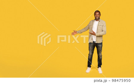 Cheerful middle aged african american male in casual showing hands on copy space, recommends ad and offer 98475950