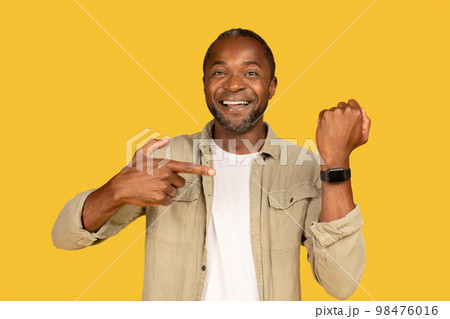 Happy middle aged african american man in casual show finger at smartwatch with blank screen Happy middle aged african american man in casual show finger at smartwatch with blank screen 98476016