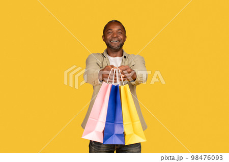 Cheerful african american middle aged man shopaholic show many packages with purchases from shop Cheerful african american middle aged man shopaholic show many packages with purchases from shop 98476093