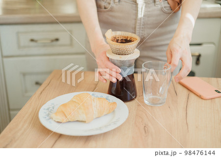 woman makes coffee in morning for breakfast, brew drip purover. americano cappuccino. woman makes coffee in morning for breakfast, brew drip purover. americano cappuccino. 98476144
