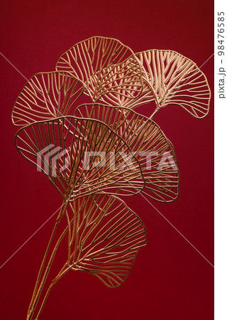 Golden Ginkgo Biloba Leaves Against Dark Red Background. Luxury Decorative Poster Print or Banner Background. 98476585