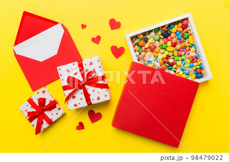 Red envelope with candy and gift box and Valentines hearts on colored background. Flat lay, top view. Romantic love letter for Holiday concept 98479022