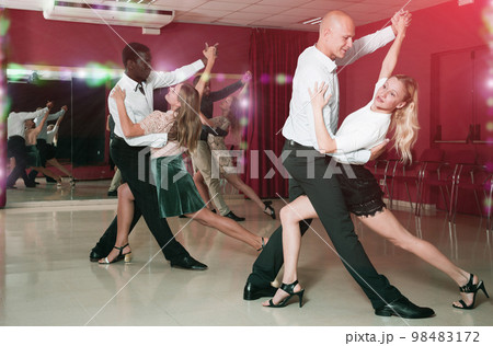 Portrait of positive adult pairs enjoying tango in modern dance hall Portrait of positive adult pairs enjoying tango in modern dance hall 98483172