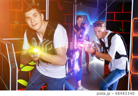 Portrait of excited guy with laser pistol playing laser tag in a Portrait of excited guy with laser pistol playing laser tag in a 98483340