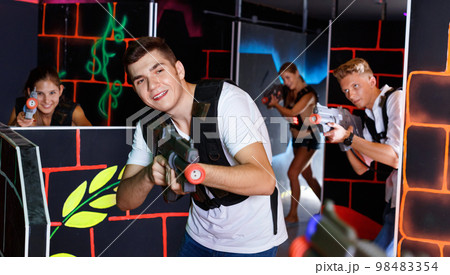 Portrait of excited guy with laser pistol playing laser tag in a 98483354