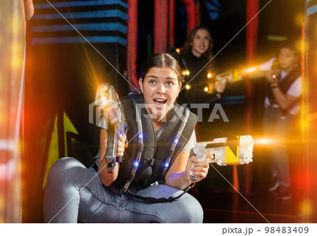Girl running and dodging while playing lasertag Girl running and dodging while playing lasertag 98483409