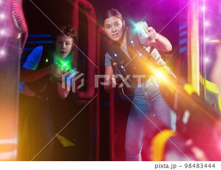 Two players guy and woman with laser weapons in dark laser tag room Two players guy and woman with laser weapons in dark laser tag room 98483444