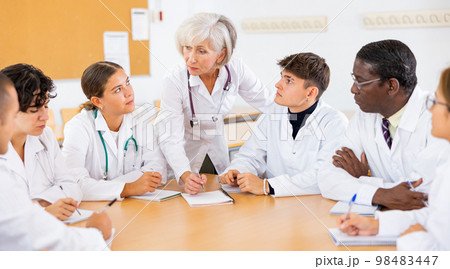 Group of medical students in white coats studying in classroom Group of medical students in white coats studying in classroom 98483447