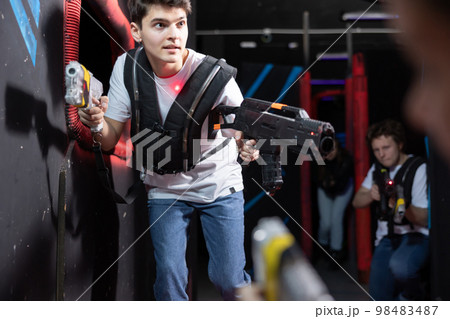 Emotional man with laser pistol playing laser tag with friends on dark labyrinth 98483487