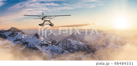 Seaplane flying over the Rocky Mountains during a colorful sunset. 98484331