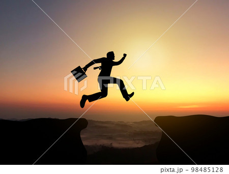 Businessman jumping to success silhouette, confident and winner or achievement in business concept Businessman jumping to success silhouette, confident and winner or achievement in business concept 98485128