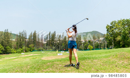 Asian golfer woman swing golf ball practice at golf driving range for relax and healthy care port. 98485803
